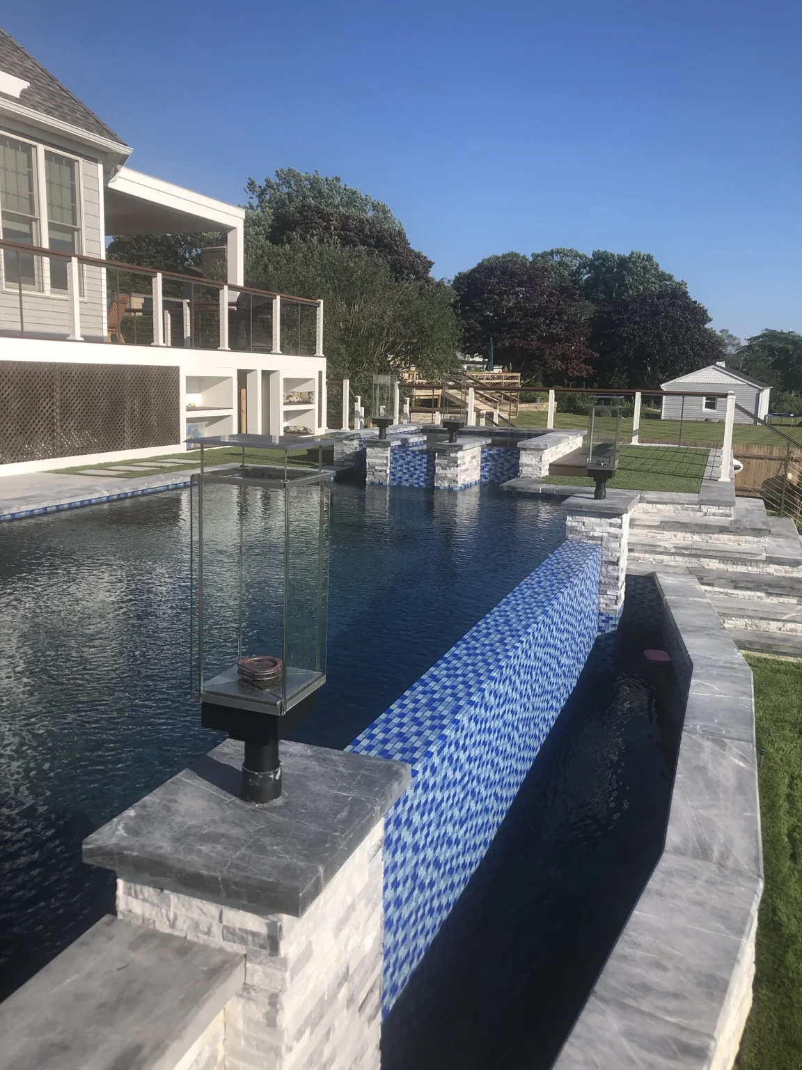 Tempest Torch on a landscape post beside a modern pool and fire-water feature