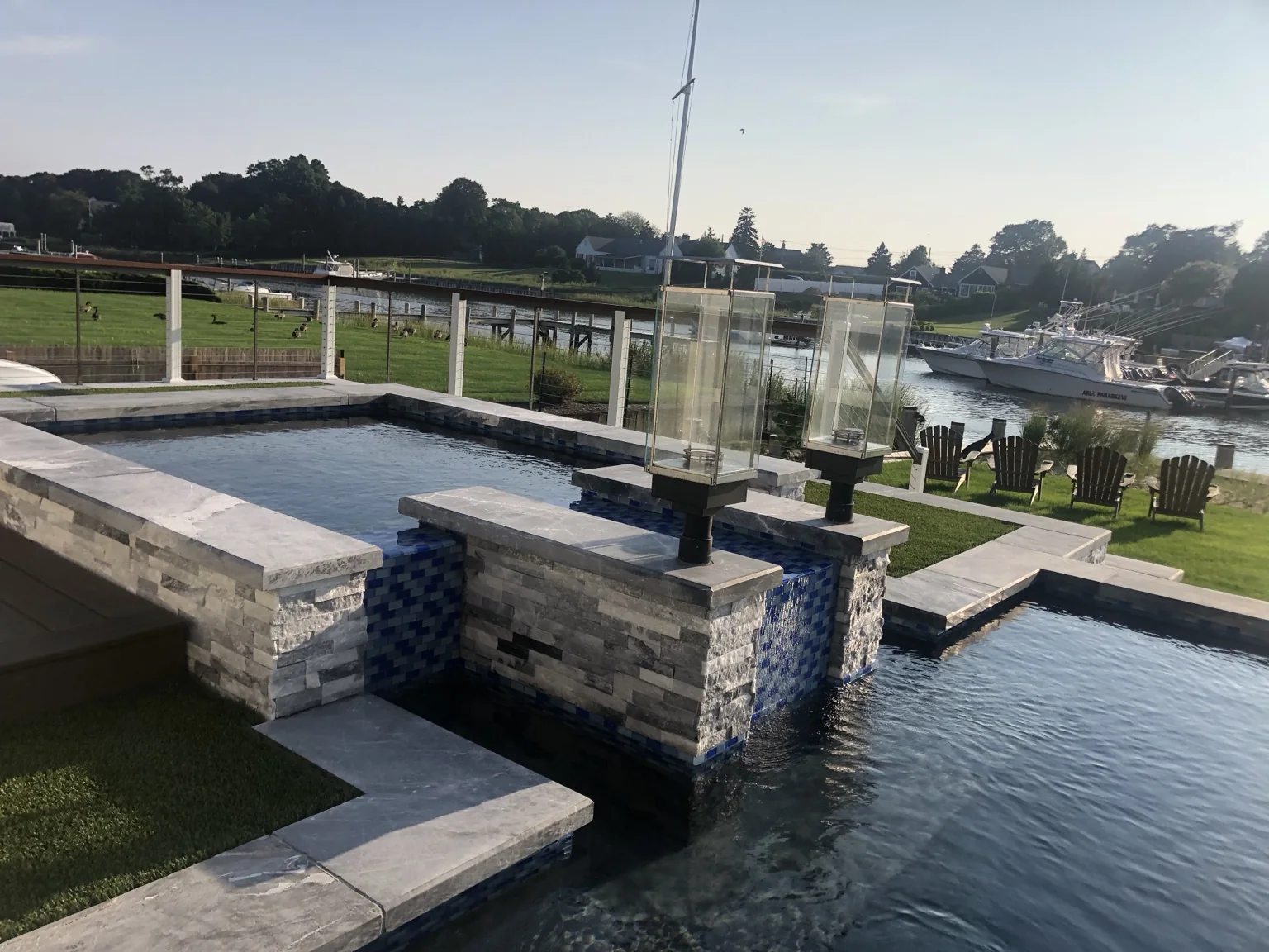 Two Tempest Torches integrated on masonry pillars within a waterfront pool design