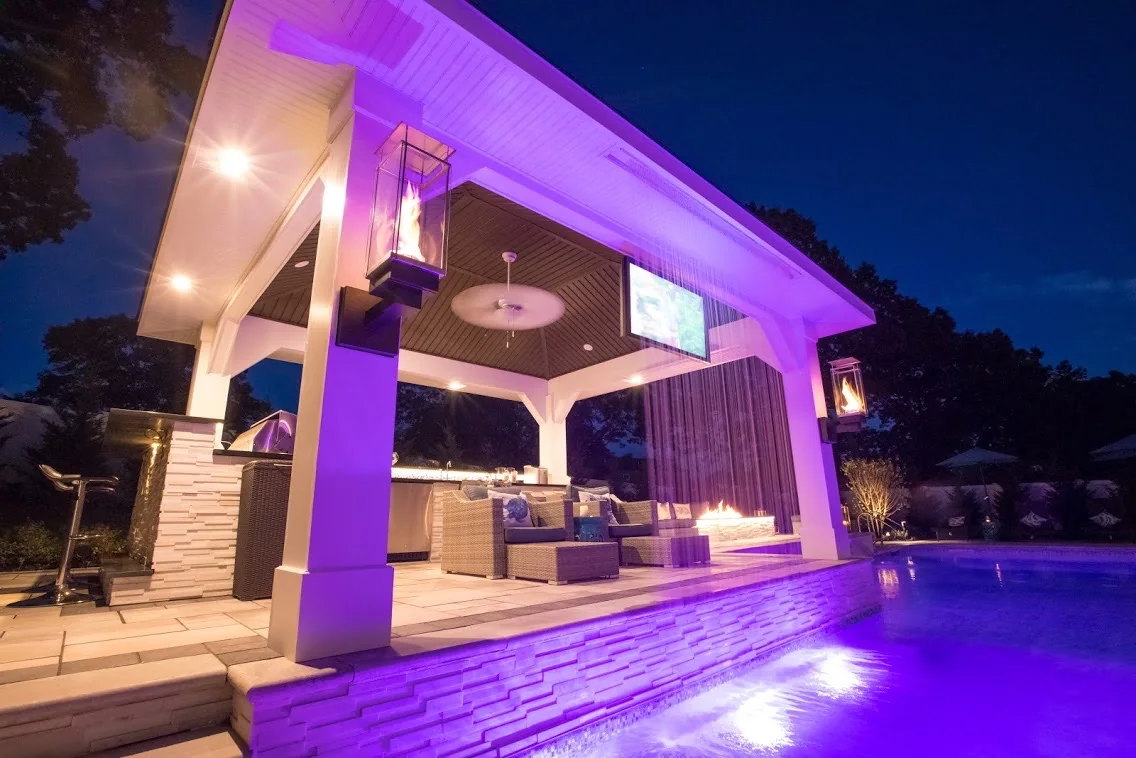 Two wall-mounted Tempest Torches framing a poolside pavilion at night