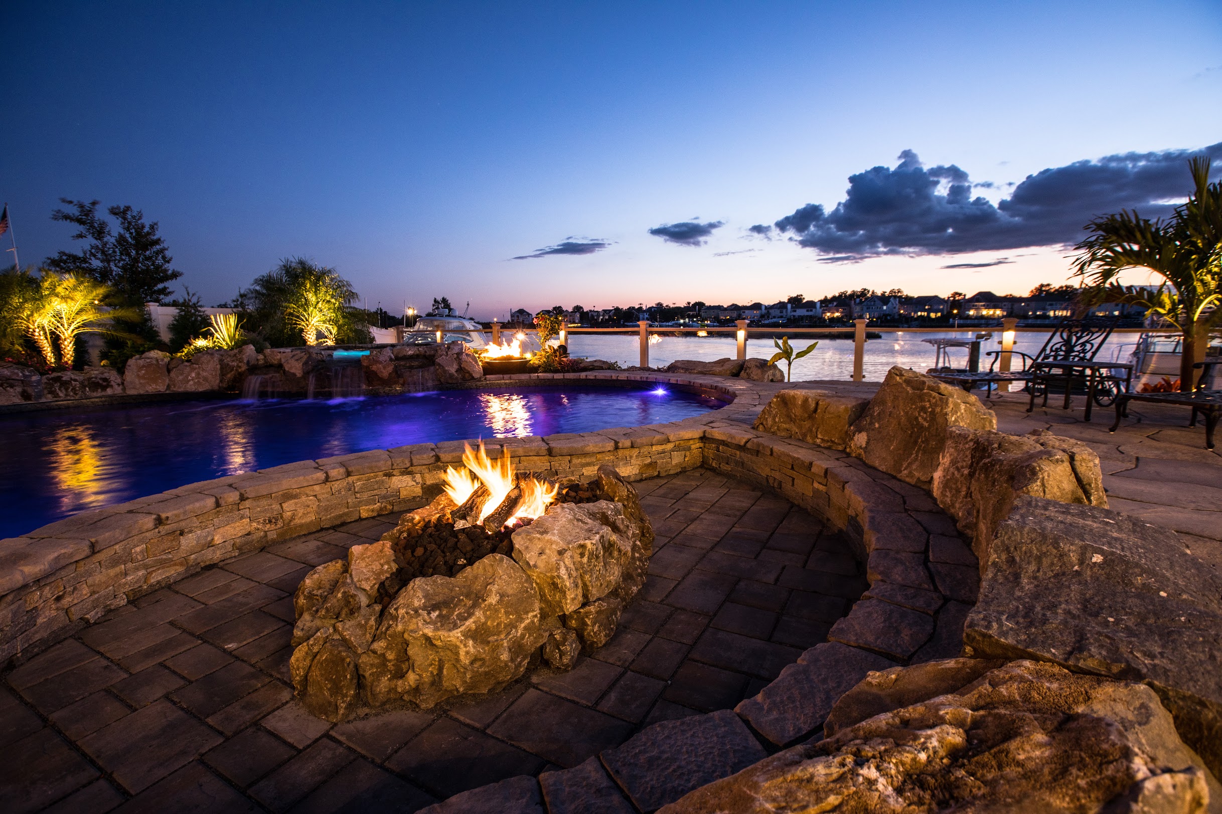 Waterfront pool and fire pit at sunset