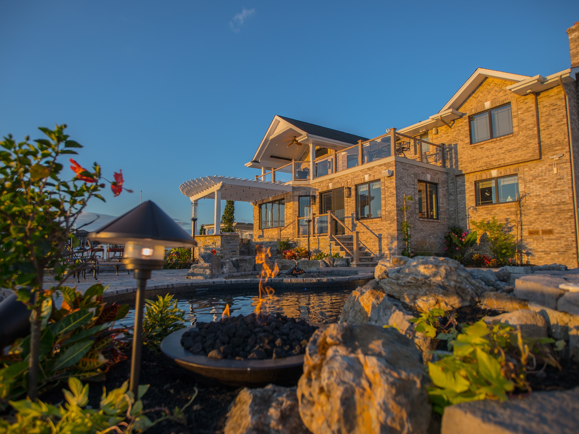 Completed waterfront backyard with fire feature and home
