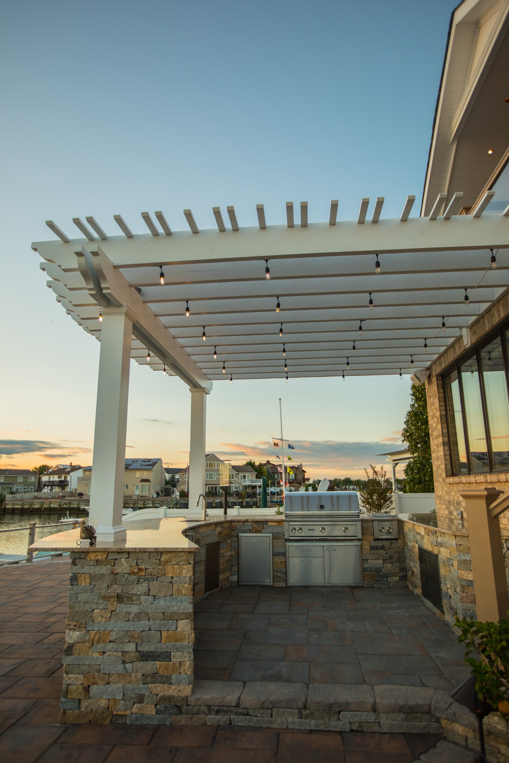 Outdoor kitchen beneath waterfront pergola