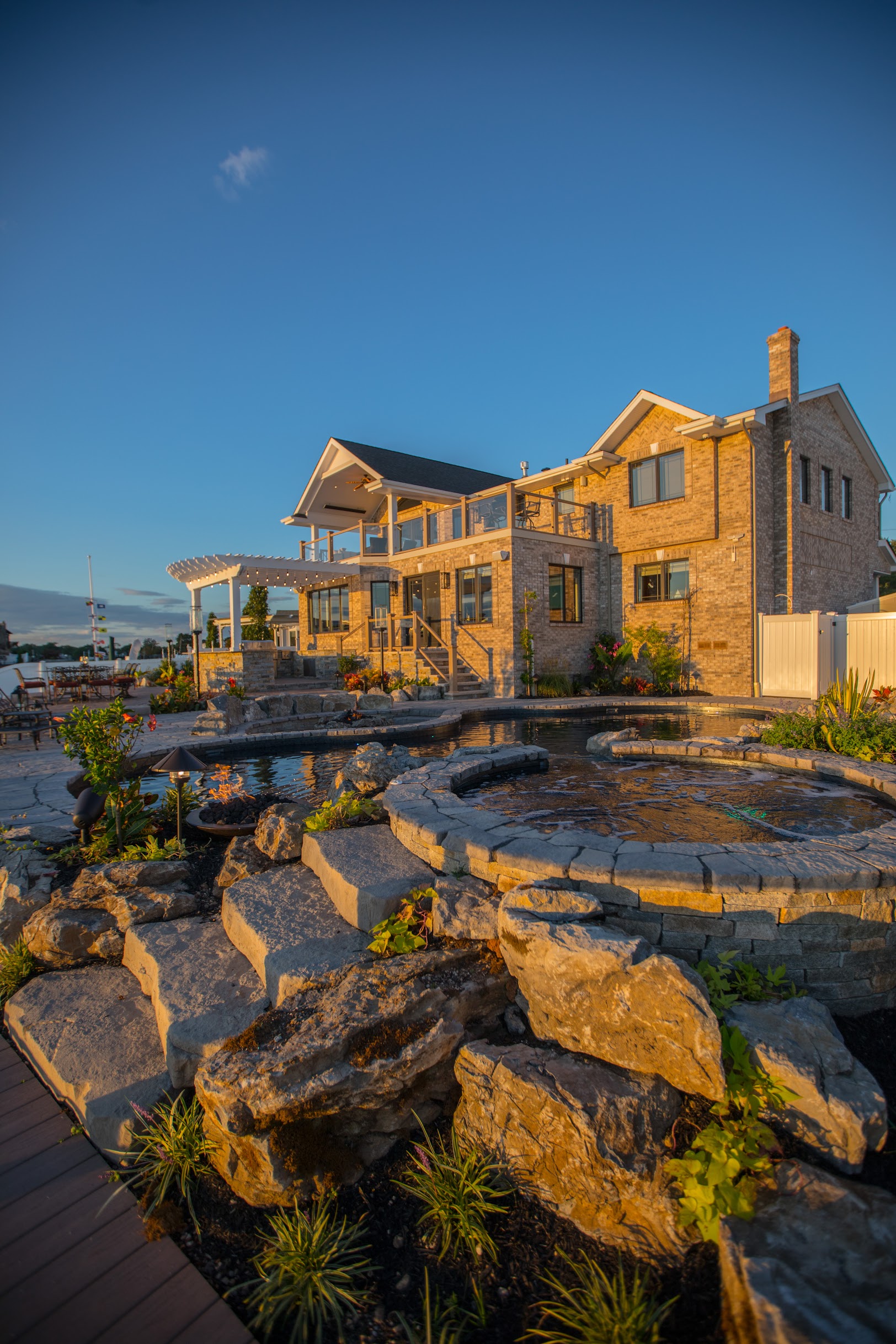 Raised spa and natural stone landscape beside waterfront home