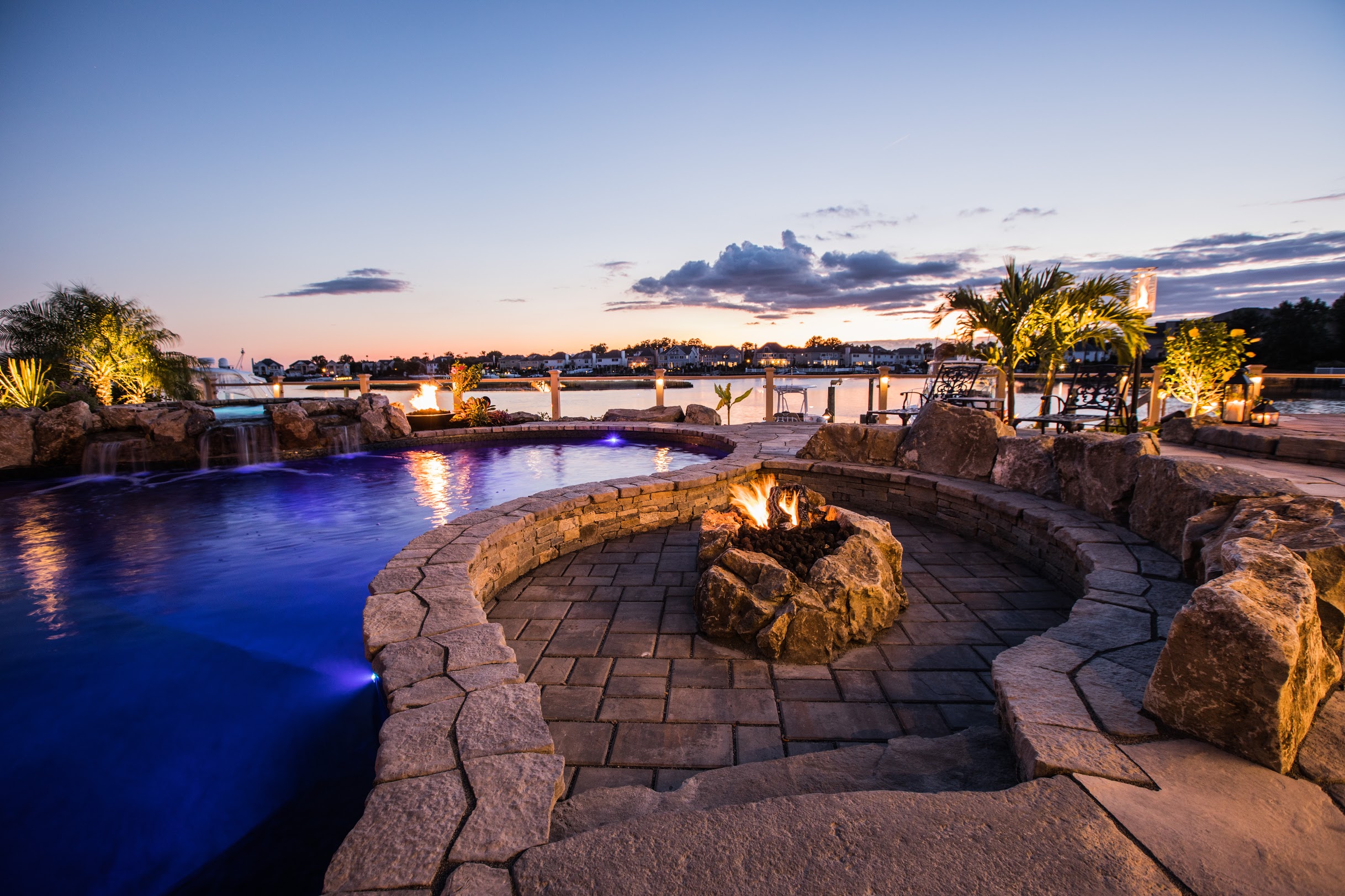 Sunken stone fire pit beside waterfront swimming pool